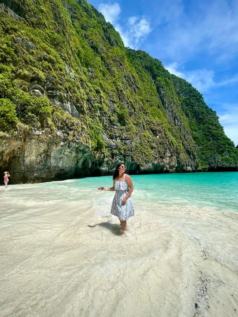 A traveller beside clear water and limestone cliffs