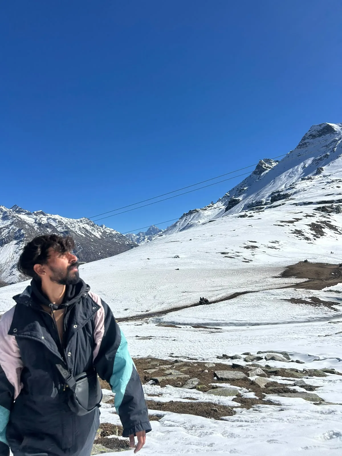 A traveller beside snow-covered mountains under a blue sky